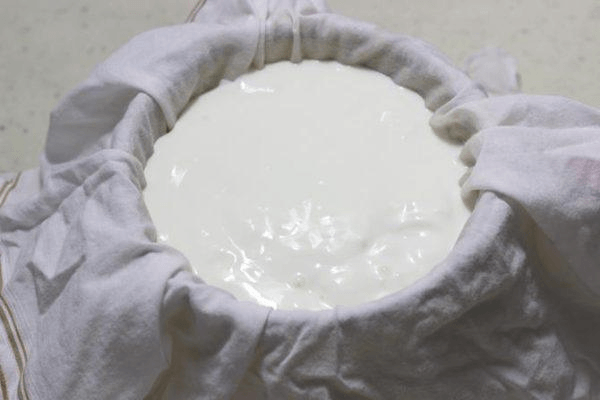 Curd poured onto muslin cloth, being prepared to hang